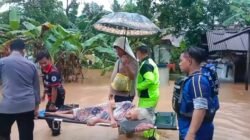 Di Bawah Guyuran Hujan, Petugas Payungi Lansia Saat Proses Evakuasi Banjir di Pamarican