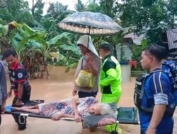 Di Bawah Guyuran Hujan, Petugas Payungi Lansia Saat Proses Evakuasi Banjir di Pamarican